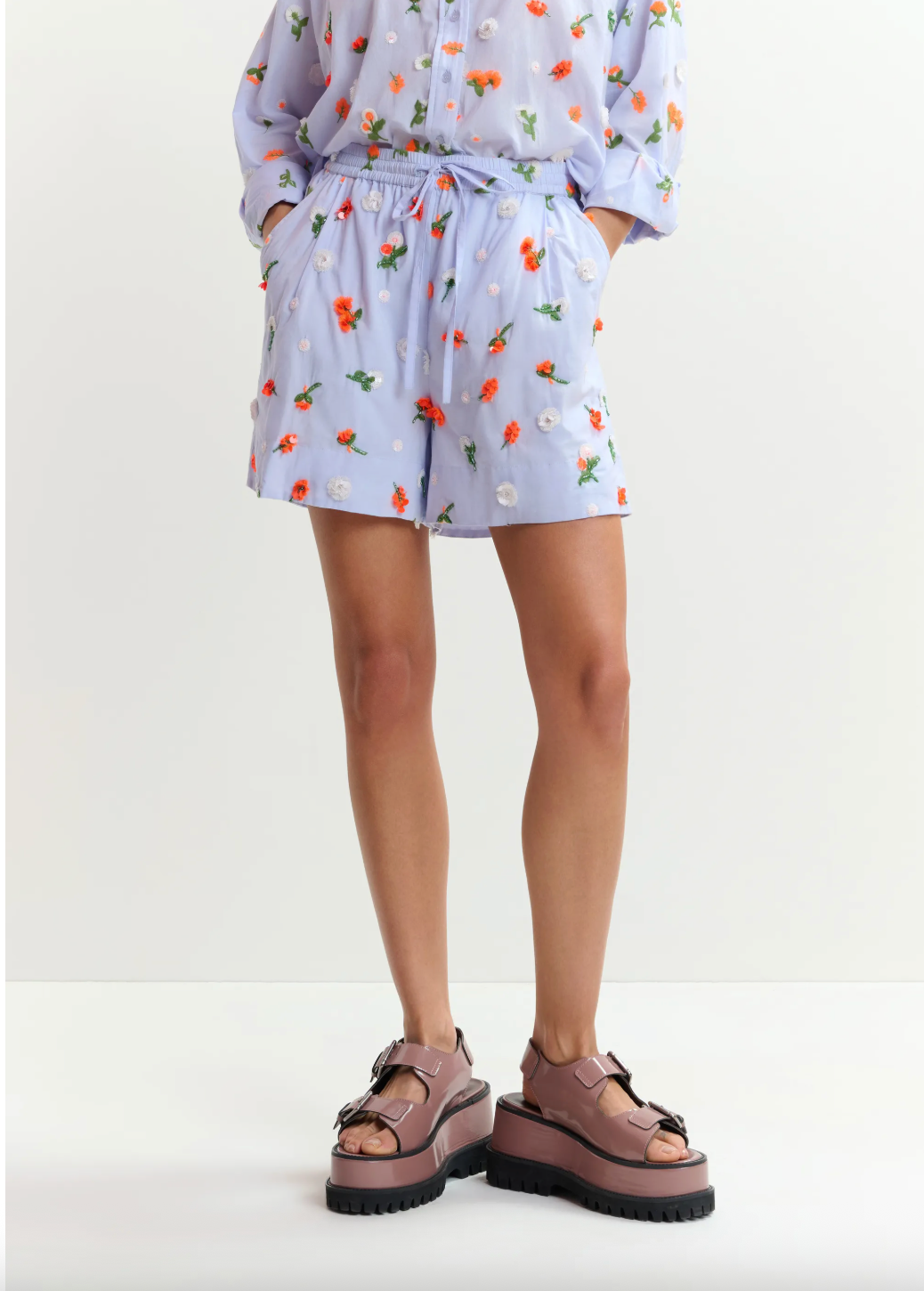 Person wearing a floral dress and platform sandals on a white background