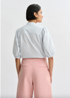 Person wearing a light blue blouse and pink pants on a white background