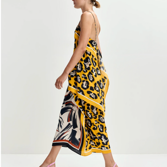 Woman wearing a yellow skirt and top  with a patterned design on a white background