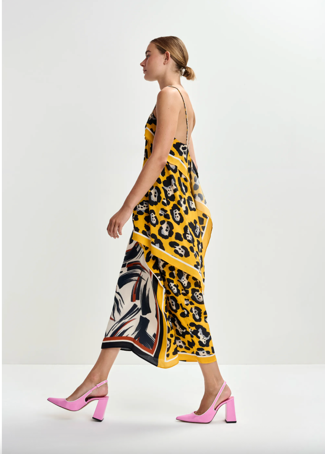 Woman wearing a yellow skirt and top  with a patterned design on a white background