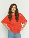 Model wearing orage lace shirt with pale wash denim