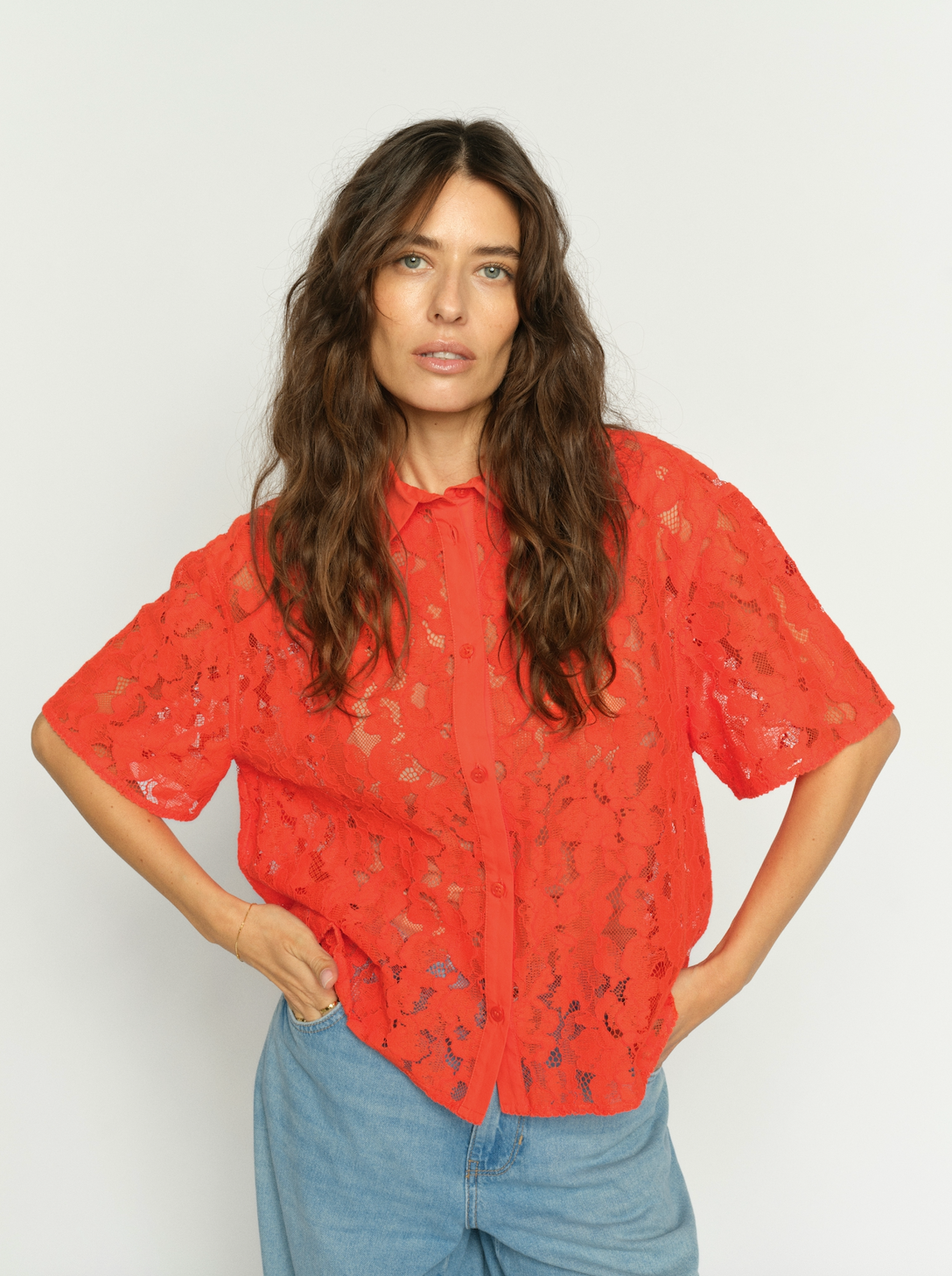 Model wearing orage lace shirt with pale wash denim
