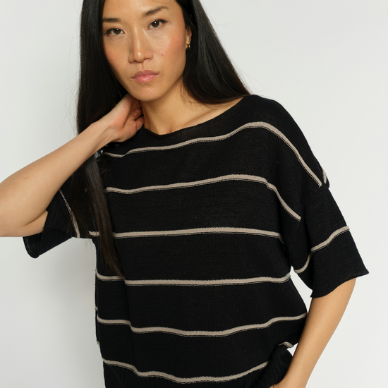 Woman wearing a black and beige striped sweater against a white background