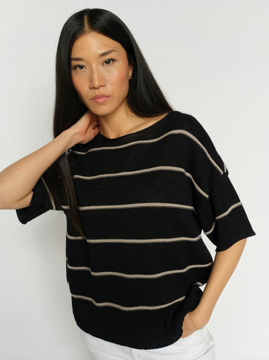 Woman wearing a black and beige striped sweater against a white background