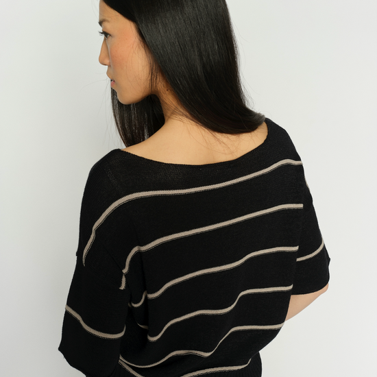 Woman wearing a black sweater with beige stripes against a white background