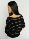 Woman wearing a black sweater with beige stripes against a white background