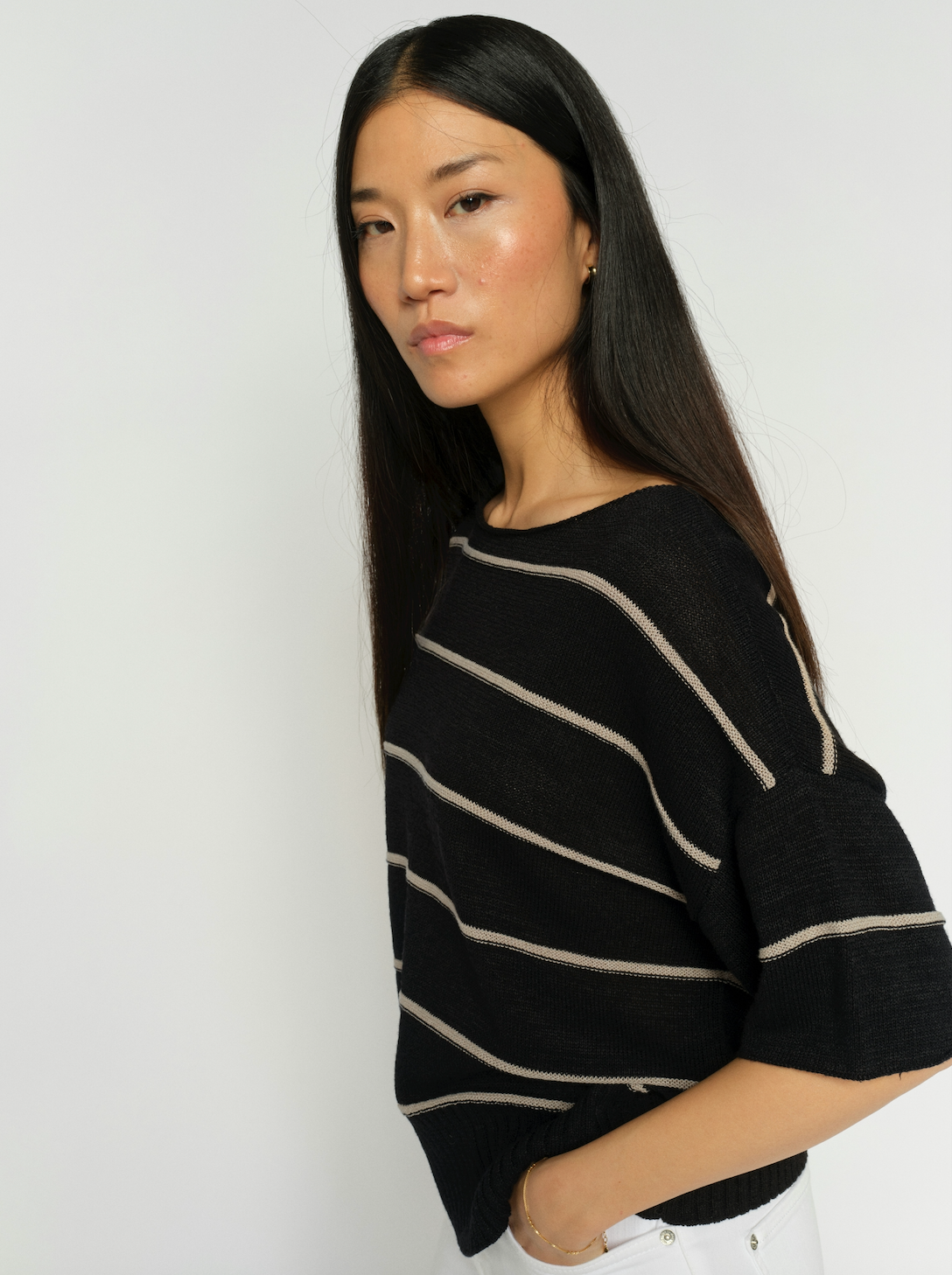 Woman wearing a black sweater with white stripes against a plain background