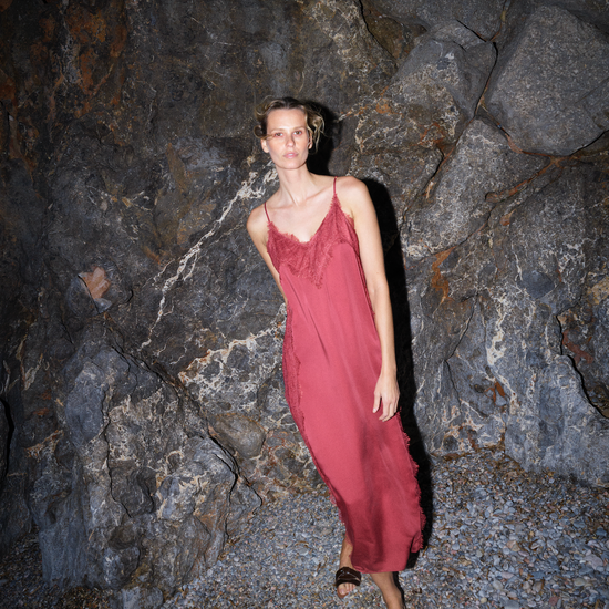 Woman in a red dress standing against a rocky wall from Mos Mosh