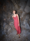 Woman in a red dress standing against a rocky wall from Mos Mosh