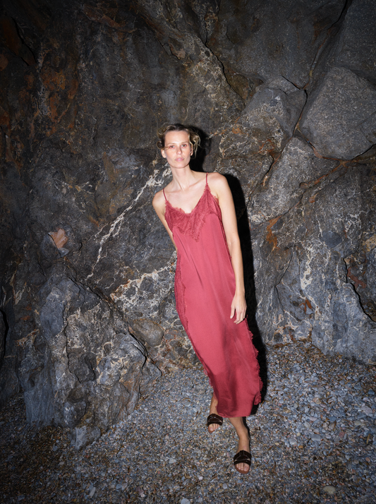 Woman in a red dress standing against a rocky wall from Mos Mosh