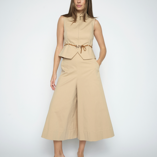 Woman wearing a beige sleeveless top and wide-leg pants on a white background