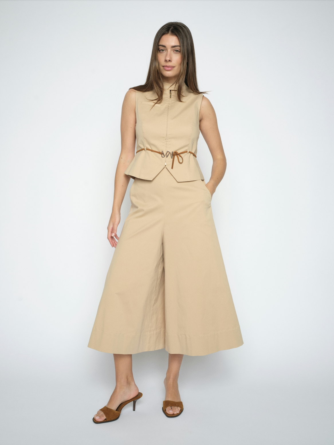 Woman wearing a beige sleeveless top and wide-leg pants on a white background