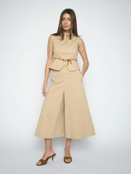 Woman wearing a beige sleeveless top and wide-leg pants on a white background