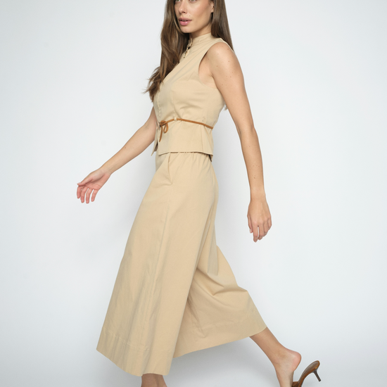 Woman wearing a beige sleeveless top and wide-leg pants on a white background