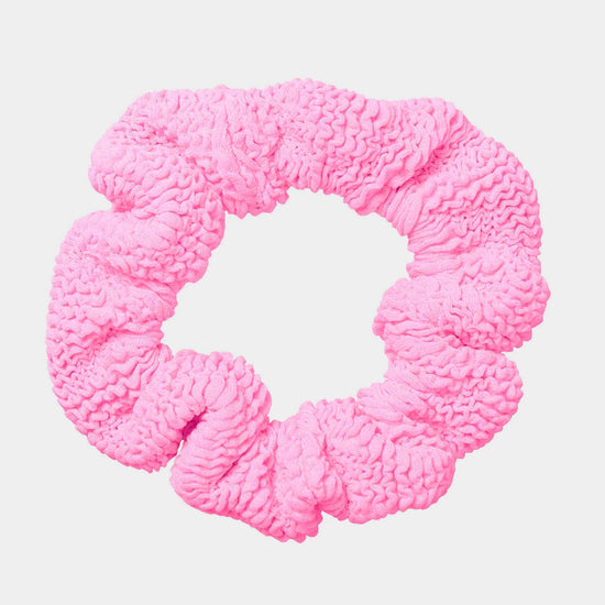 Pink textured scrunchie on a light pink background