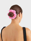 Woman with a pink hair towel wrapped around her bun against a light gray background