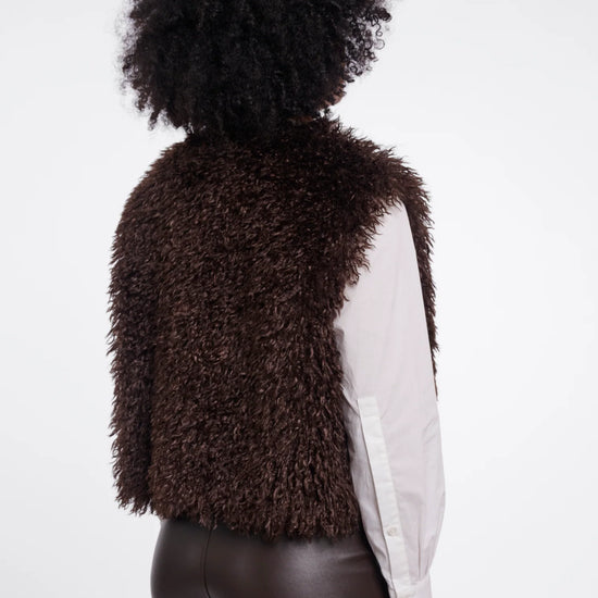 Person wearing a brown fluffy vest on a white background