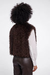 Person wearing a brown fluffy vest on a white background