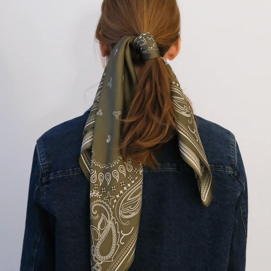 Person wearing a patterned scarf around their neck with a plain background