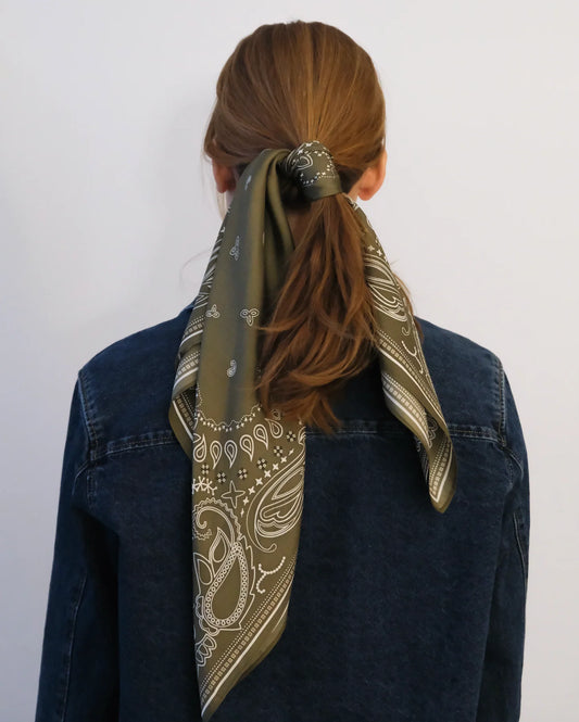Person wearing a patterned scarf around their neck with a plain background