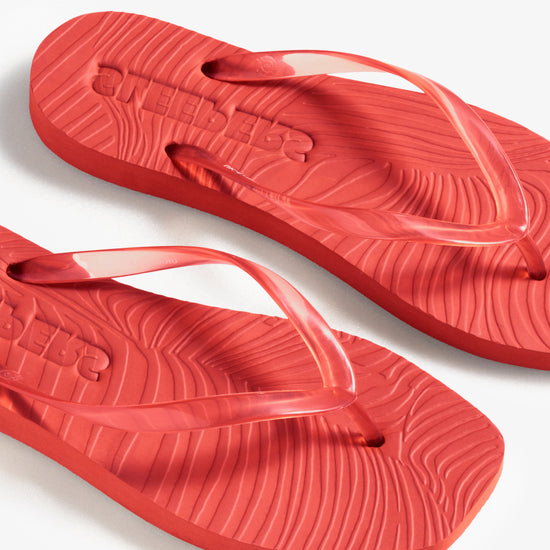 Red flip-flops on a white background birds eye view