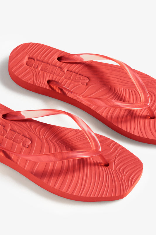 Red flip-flops on a white background birds eye view
