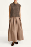 Woman wearing a brown sleeveless top and long skirt on a white background