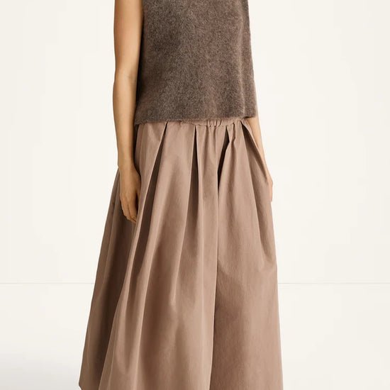 Woman wearing a brown sleeveless top and long skirt on a white background