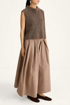 Woman wearing a brown sleeveless top and long skirt on a white background
