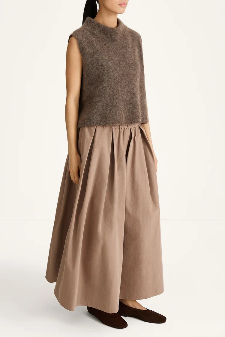 Woman wearing a brown sleeveless top and long skirt on a white background