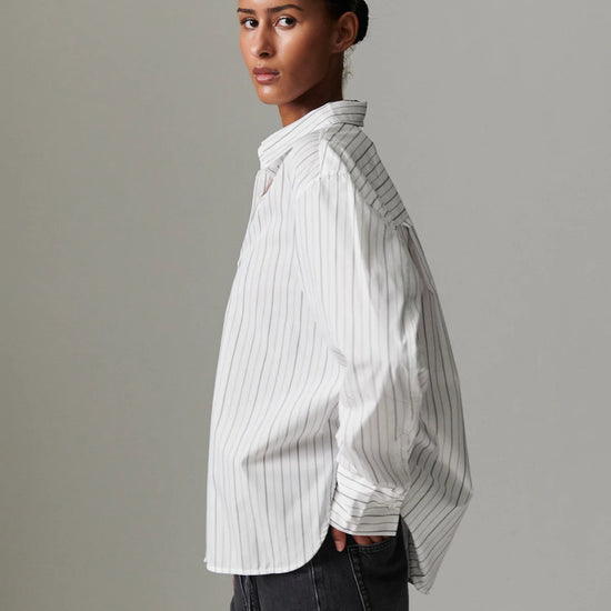 Woman wearing a white pinstripe shirt against a gray background