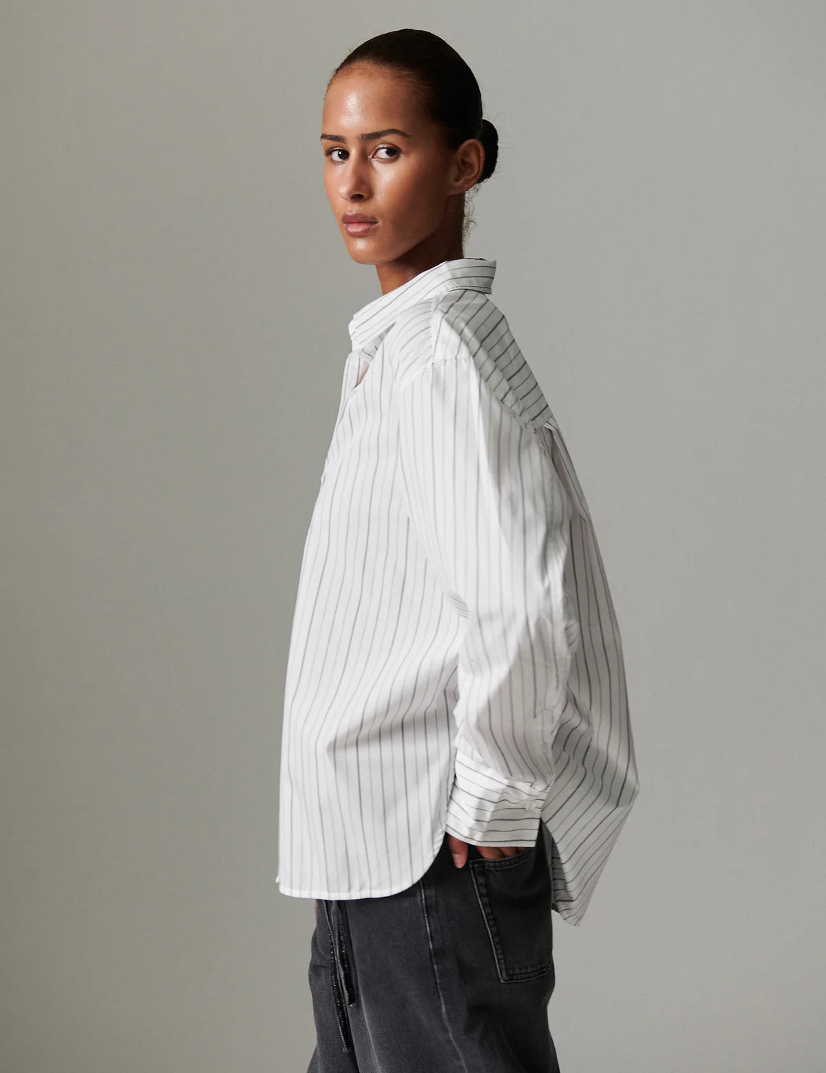 Woman wearing a white pinstripe shirt against a gray background