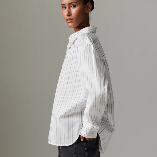 Person wearing a white pinstripe shirt against a gray background