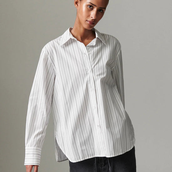 Woman wearing a white striped shirt against a gray background