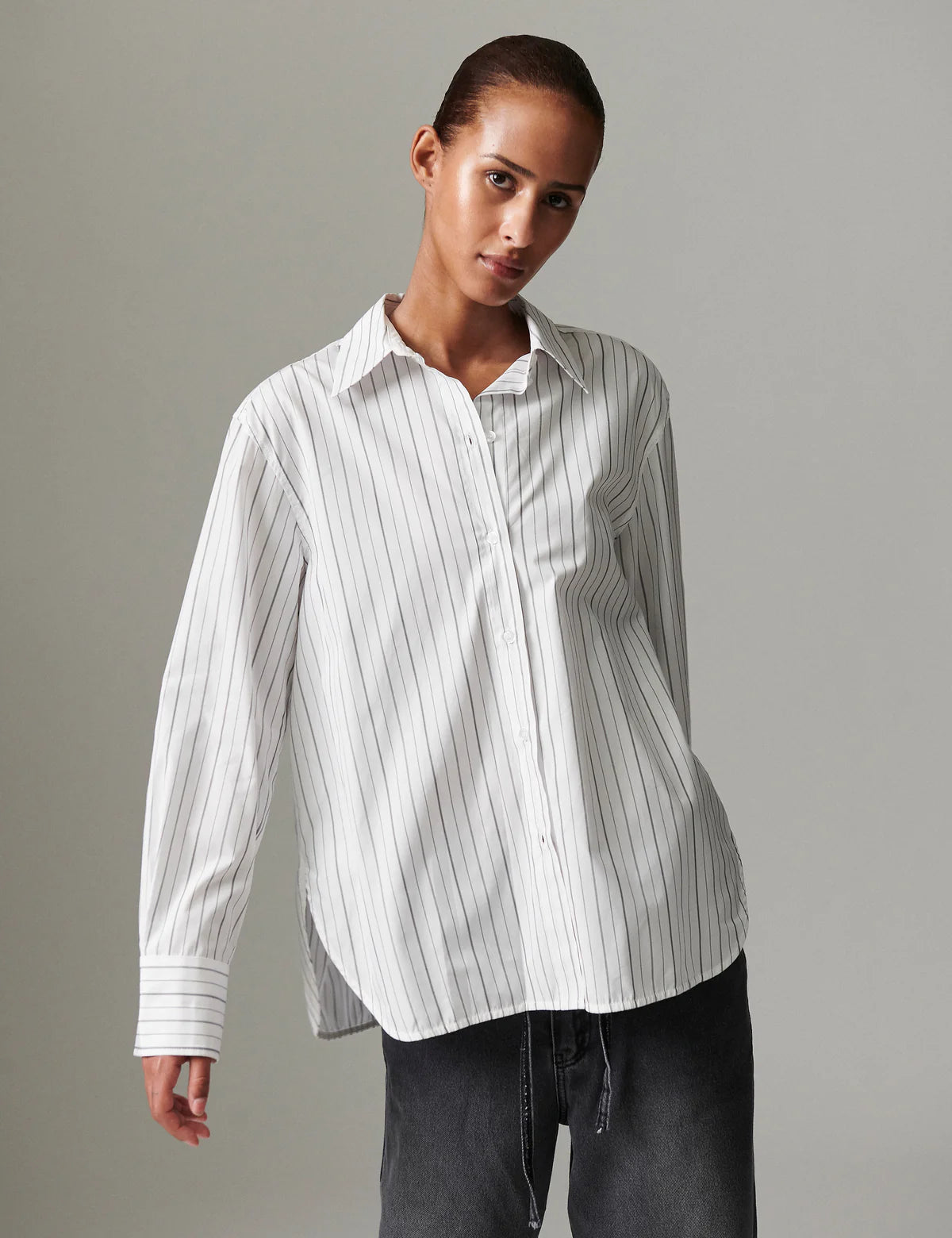 Woman wearing a white striped shirt against a gray background