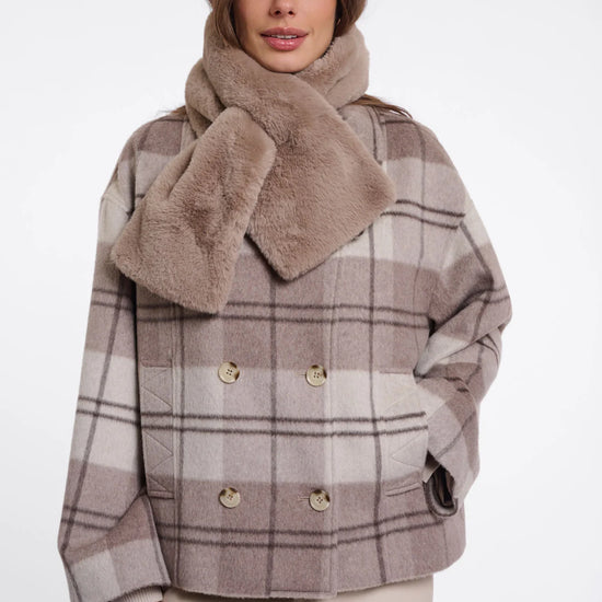Woman wearing a plaid coat with a fur collar on a white background