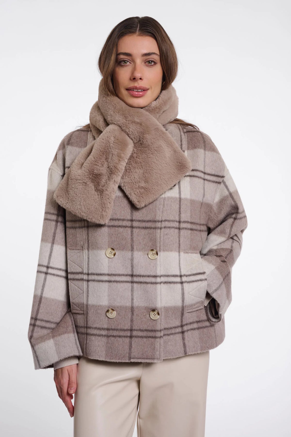 Woman wearing a plaid coat with a fur collar on a white background