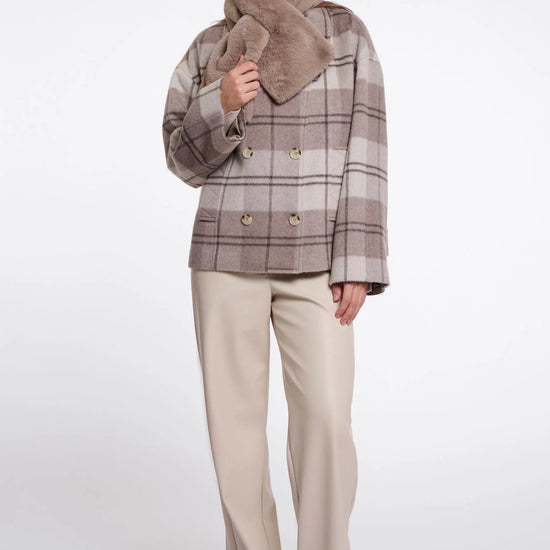 Woman wearing a plaid coat with a fur-lined hood on a white background