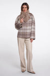 Woman wearing a plaid coat with a fur-lined hood on a white background