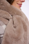 Close-up of a person wearing a plush taupe faux fur coat, showing the soft texture and collar detail.