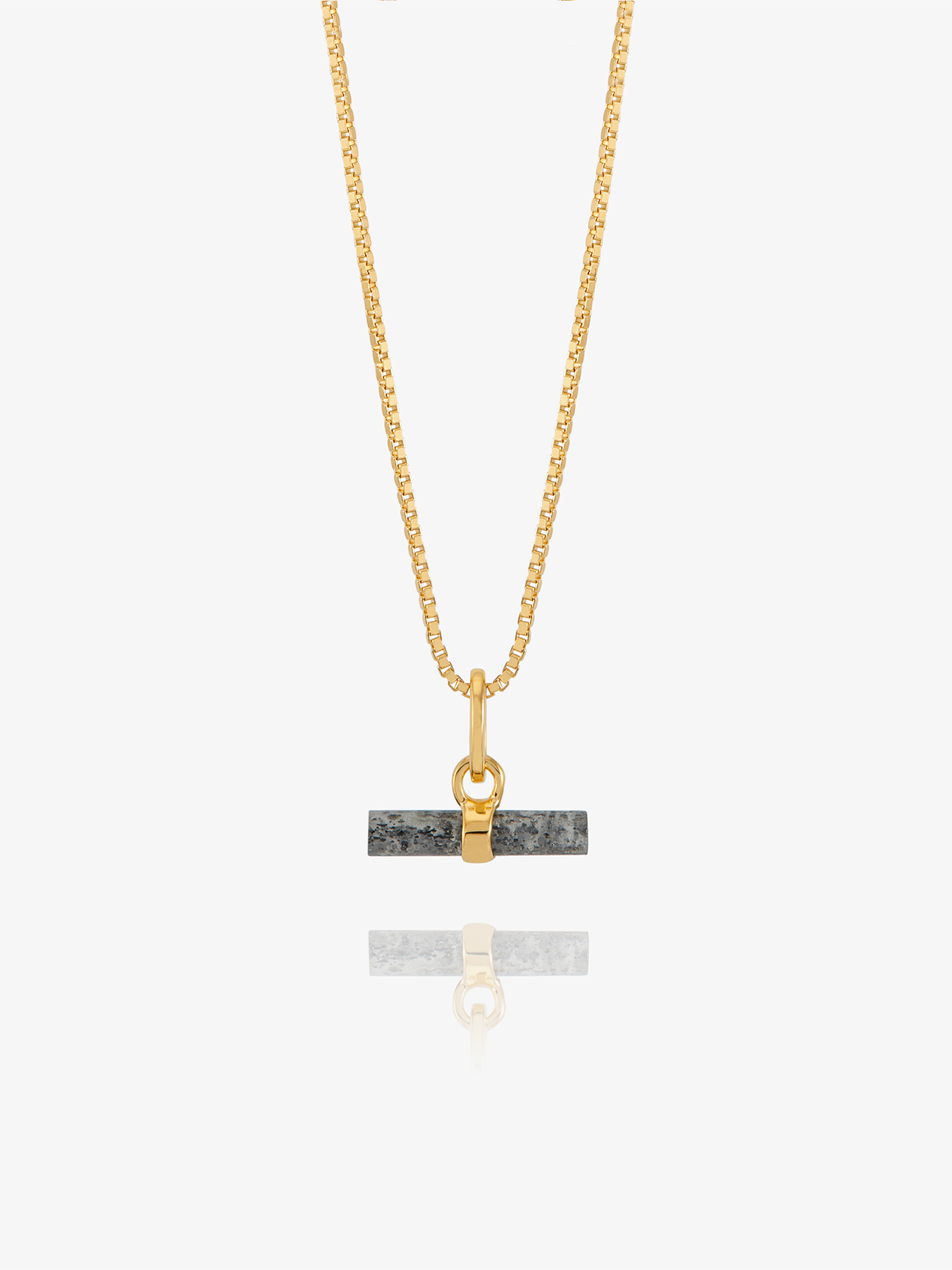 A gold chain necklace with a rectangular dark gray stone pendant featuring a gold split ring and clasp, displayed against a light gray background with a soft reflection below.