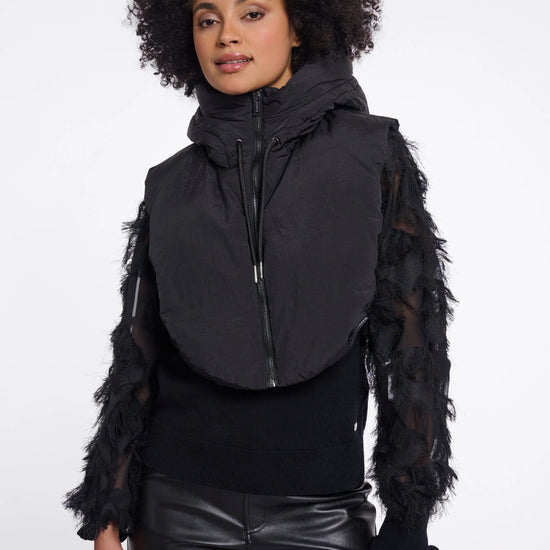 Woman wearing a black vest with sheer sleeves on a white background