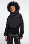 Woman wearing a black vest with sheer sleeves on a white background
