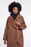 Woman wearing a brown coat with gold buttons on a white background