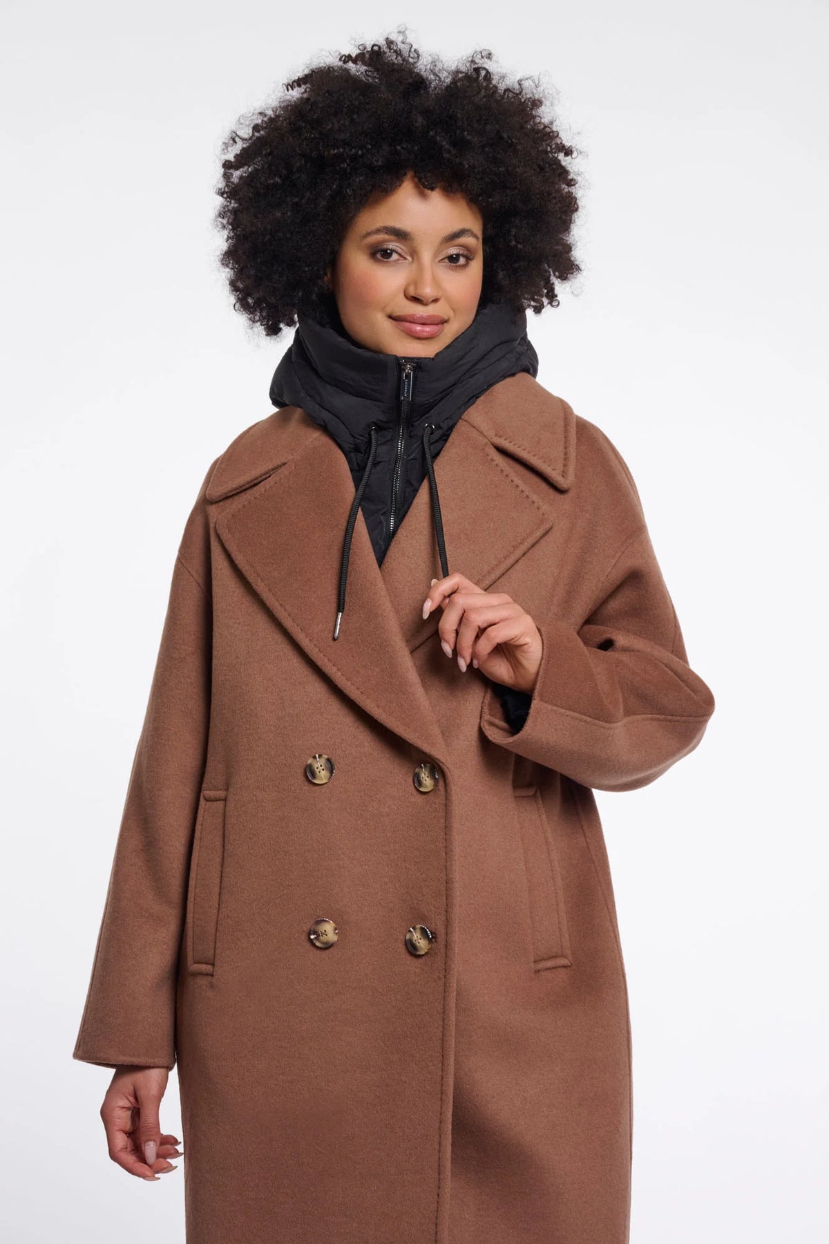 Woman wearing a brown coat with gold buttons on a white background