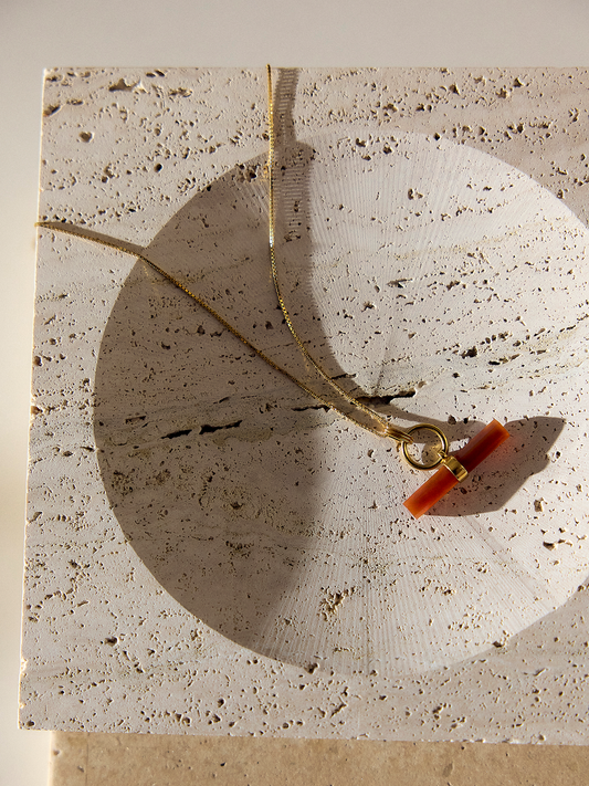 gold ring necklace with orange bar on a gold chain form rachel jackson on a stone
