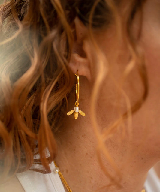 Large gold hoop earrings with flying bee pendants and a rice pearl drop with butterfly earring fastenings