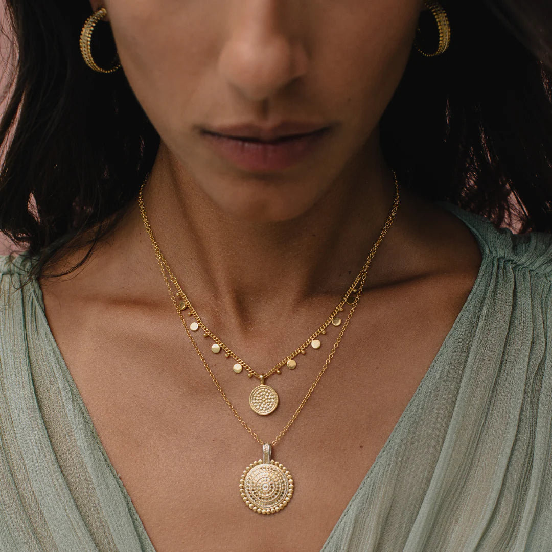 Close-up of a woman wearing gold necklaces and earrings from Anna Beck