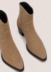 A pair of pointed-toe ankle boots in tan suede with black soles and low block heels, shown on a light beige background.