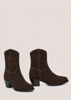 A pair of dark brown suede western-style ankle boots with low block heels, shown from the side and back-three-quarter angles against a solid light beige background.